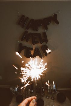 a person holding a sparkler in front of a sign that says happy new year