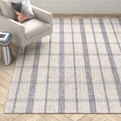 a white chair sitting on top of a wooden floor next to a gray and white rug