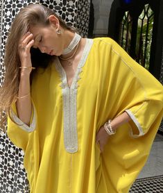 Illuminate your style with our Crepe Oversized Kaftan in the radiant Yellow color. This kaftan beautifully combines tradition and modernity, showcasing the artistry of Moroccan craftsmanship.   Product Details:      V-Neck Kaftan with Handmade "Sfeefa" Finish : The Crepe Oversized Kaftan features an elegant V-neck design adorned with our signature handmade "sfeefa" for a touch of Moroccan opulence.     Handmade Embroideries : Delicate handmade embroideries grace the neckline and front of this ka Elegant Yellow Kaftan For Festive Occasions, Yellow Bohemian Kaftan For Festive Occasions, Yellow Bohemian Kaftan For Festive Season, Elegant Yellow Kaftan For Eid, Festive Yellow Bohemian Kaftan, Festive Bohemian Yellow Kaftan, Elegant Summer Tunic Thobe, Elegant V-neck Festival Kaftan, Spring Festive Kaftan Tunic