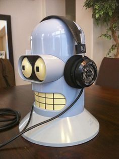 a blue robot headphone holder sitting on top of a wooden table