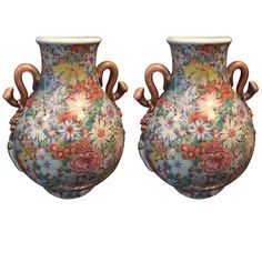 two vases with handles decorated with flowers