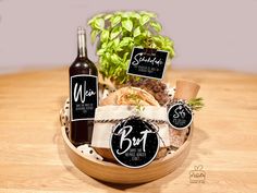 a wine bottle and some food in a basket on a wooden table with two signs