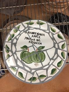 a ceramic plate with green leaves on it sitting on a wire rack next to other items