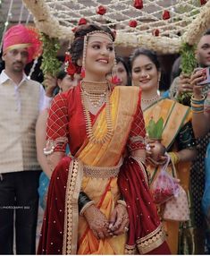 a woman in a red and yellow sari is standing with other people around her