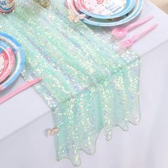 the table is set with plates, cups and napkins for an unicorn themed birthday party