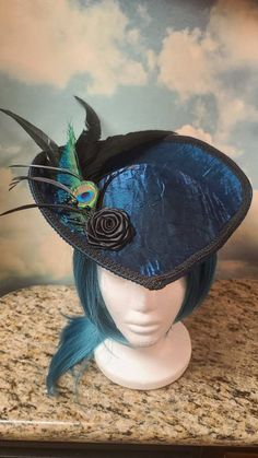 Beautiful Teal Victorian Inspired Hat with a Black Rose, Peacock and Black Feathers. Perfect for dressing up, formal events, Vampire Balls, and cosplay. Other styles are available in all colors. Message me for a custom order. Made in a pet friendly studio. Made to order. 3 to 5 days creation time. Check out my other listings: Black Velvet Victorian with Tassels: https://www.etsy.com/listing/1197594531/black-velvet-formal-hat-velvet-top-hat Silver Victorian: https://www.etsy.com/listing/1293744756/victorian-hat-edwardian-hat-downton Mauve Victorian:  https://www.etsy.com/listing/1293745798/mauve-velvet-hat-formal-hat-red-top-hat Burgandy Victorian:  https://www.etsy.com/listing/1094341893/victorian-hat-edwardian-hat-downton Turquoise Peacock: https://www.etsy.com/listing/1101444884/turquois Peacock Hat, Pirate Captain Hat, Fantasy Hat, Steampunk Hats, Feathered Hat, Tea Hat, Teal Hat, Hat With Feather, Mauve Velvet