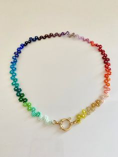 a rainbow necklace with a gold clasp on the end and beads hanging down from it