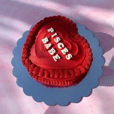 a red heart shaped cake with the words peace on it sitting on a pink tablecloth