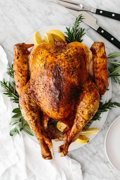 a roasted turkey on a plate with lemons and rosemary