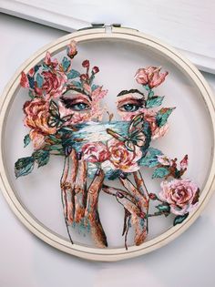 an embroidery project with flowers and hands in the shape of a woman's face