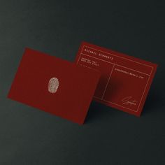 a red business card with a fingerprint on the front and back side, sitting on a black surface