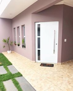 a white door sitting next to a lush green field on the side of a building