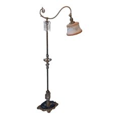 an old fashioned floor lamp with a glass shade on it's arm and base