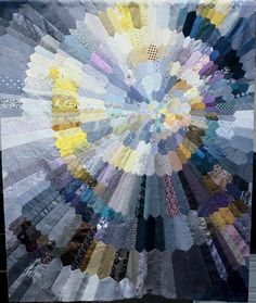 a very large quilt with many different colors on it's sides and the center is made out of strips of fabric