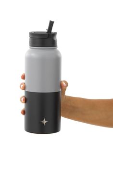 a hand holding a gray and black insulated water bottle with a straw in it