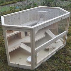 a bird cage sitting in the grass on top of a wooden box with stairs leading up to it