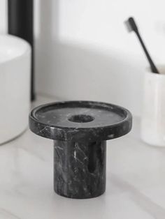 a marble pedestal with a toothbrush holder in the middle on a white countertop