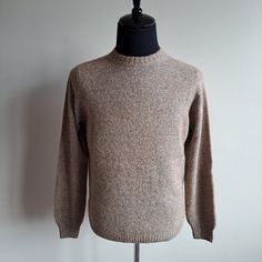 a sweater on a mannequin with a black topper and white wall in the background