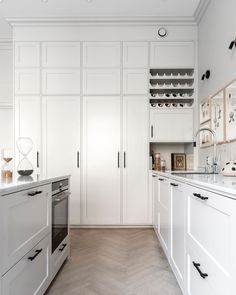 a kitchen with white cabinets and wood flooring is pictured in this image, there are wine racks on the wall