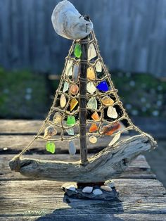 a small glass christmas tree sitting on top of a wooden table next to a fence