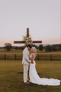 a bride and groom standing in front of a cross