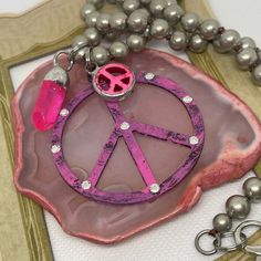 This Pink Metal Peace Sign Necklace Features A 2" Metal Peace Sign Pendant Adorned With Crystal Embellishments. The Pendant Hangs On A Stylish 20" Silver Chain, Adding A Touch Of Elegance To Any Outfit. In Addition, The Necklace Includes Two Charming Pink Charms That Enhance Its Boho Appeal. The Mixed Metal Navajo Style Design Adds A Unique And Trendy Element To This Statement Piece. Nickel-free Silver Charm Necklace, Pink Metal Charm Necklaces, Pink Nickel-free Metal Charm Necklaces, Nickel Free Pink Metal Charm Necklaces, Nickel-free Pink Metal Charm Necklaces, Silver Spiritual Charm Necklace, Silver Charm Necklace Gift, Pink Nickel-free Metal Necklace, Nickel-free Pink Metal Necklaces