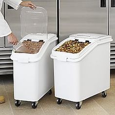 a woman standing next to two bins filled with food