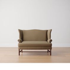 a tan chair sitting on top of a hard wood floor next to a white wall