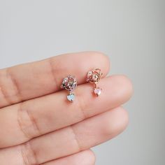 someone is holding two small diamond studs in their left hand and the other one has an earring on it