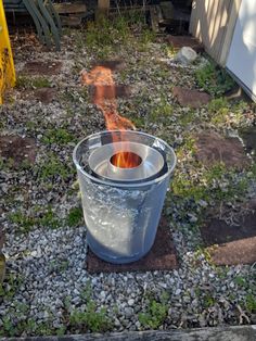 a bucket with fire coming out of it sitting on the ground next to a building