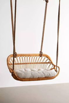 a wicker hanging chair with cushions on the front and back, attached to a rope frame