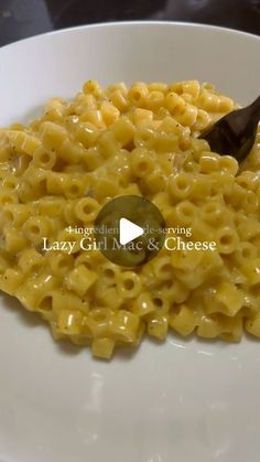 macaroni and cheese is being served on a white plate with a black spoon