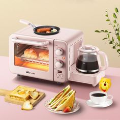 a pink toaster oven sitting on top of a counter next to bread and coffee