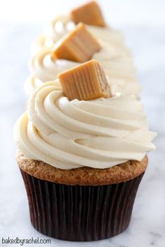 two cupcakes with white frosting and peanut butter on top are sitting on a marble surface