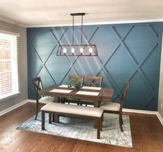 a dining room with blue walls and wooden flooring is pictured in this image, there are four chairs around the table