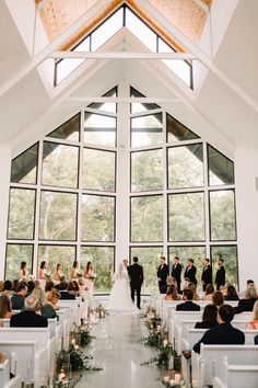 a bride and groom walking down the aisle at their wedding ceremony in front of large windows