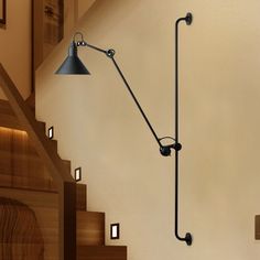 a wall mounted lamp on the side of a stair case next to a wooden banister