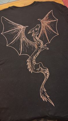 a black t - shirt with a dragon drawn on it