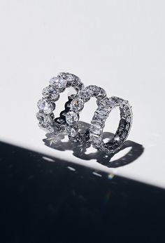 two diamond rings sitting on top of a white table next to a shadowless wall