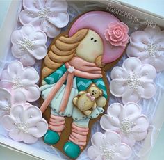 a decorated cookie in the shape of a girl holding a teddy bear