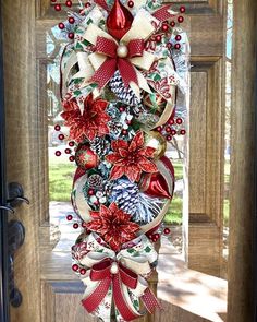 a christmas door decoration with poinsettis and bows on the front door,