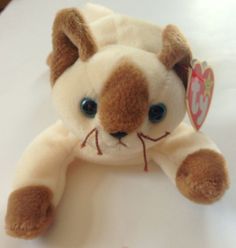 a brown and white stuffed animal with blue eyes sitting on top of a table next to a tag