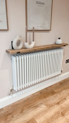 a radiator in the corner of a room with pictures on the wall behind it