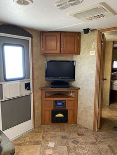 the inside of a travel trailer with an entertainment center and television in it's corner