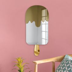 a mirror hanging on the wall above a chair with a potted plant next to it