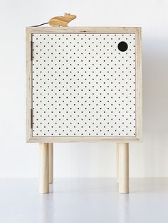 a white cabinet with black dots on it and a wooden mouse sitting on the top