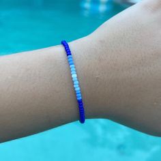 a person's arm with a blue and white beaded bracelet on it next to a swimming pool