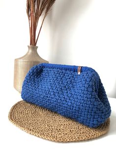 a blue crocheted purse sitting on top of a mat next to a vase