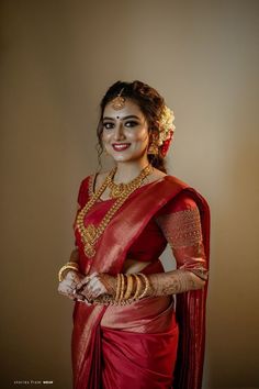 a woman wearing a red sari and gold jewelry