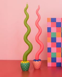 two colorful vases sitting on top of a table next to a pink and green box